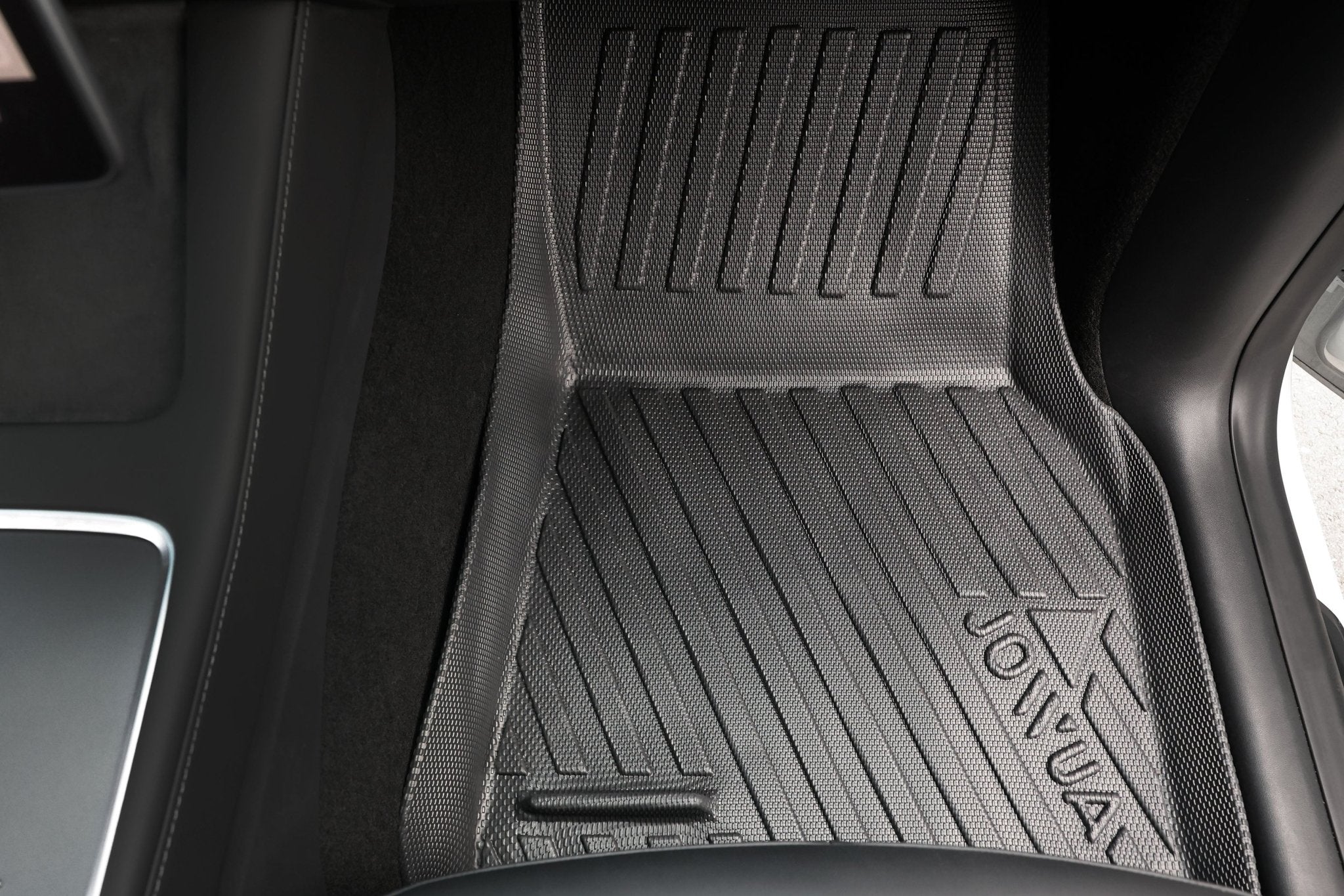 Close-up of a black rubber floor mat from the Premium Interior Essentials Set (RHD) – Model Y Juniper (2025+) by JOWUA, featuring textured grooves for traction and dirt capture, fitted in the footwell of a Right Hand Drive vehicle.