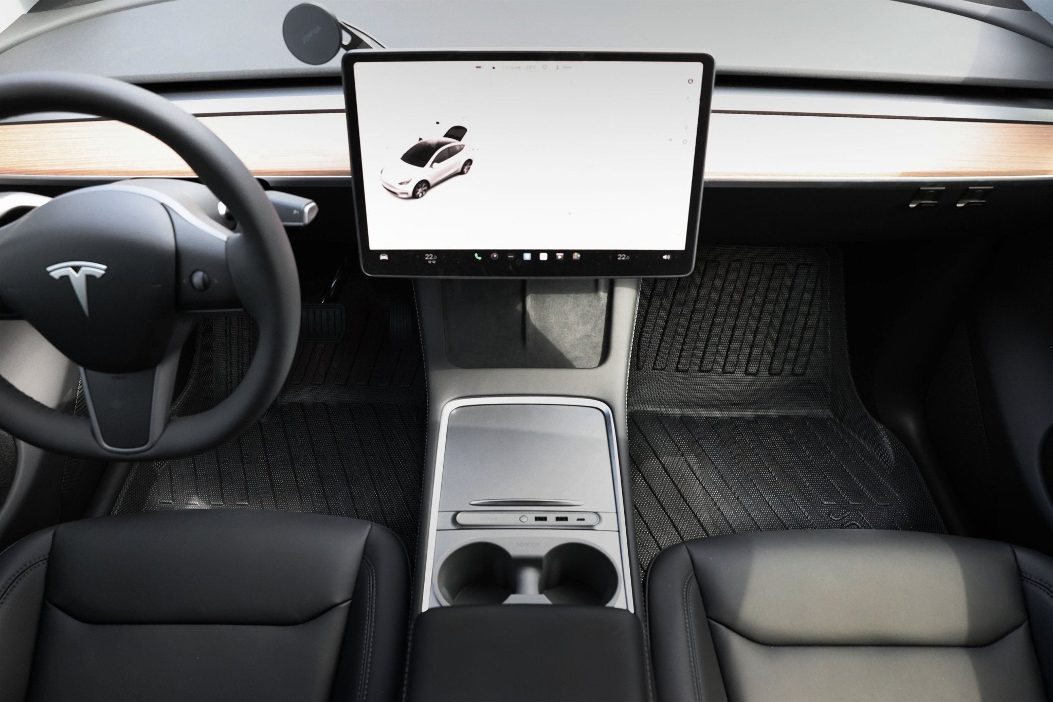 Interior of a Tesla Model Y with JOWUA’s Model Y All-Weather Floor Liners Combo—Juniper Compatible (Right Hand Drive)—showing the minimalist dashboard, cup holder console, touchscreen display, and sleek black seats. Perfect for Tesla enthusiasts.