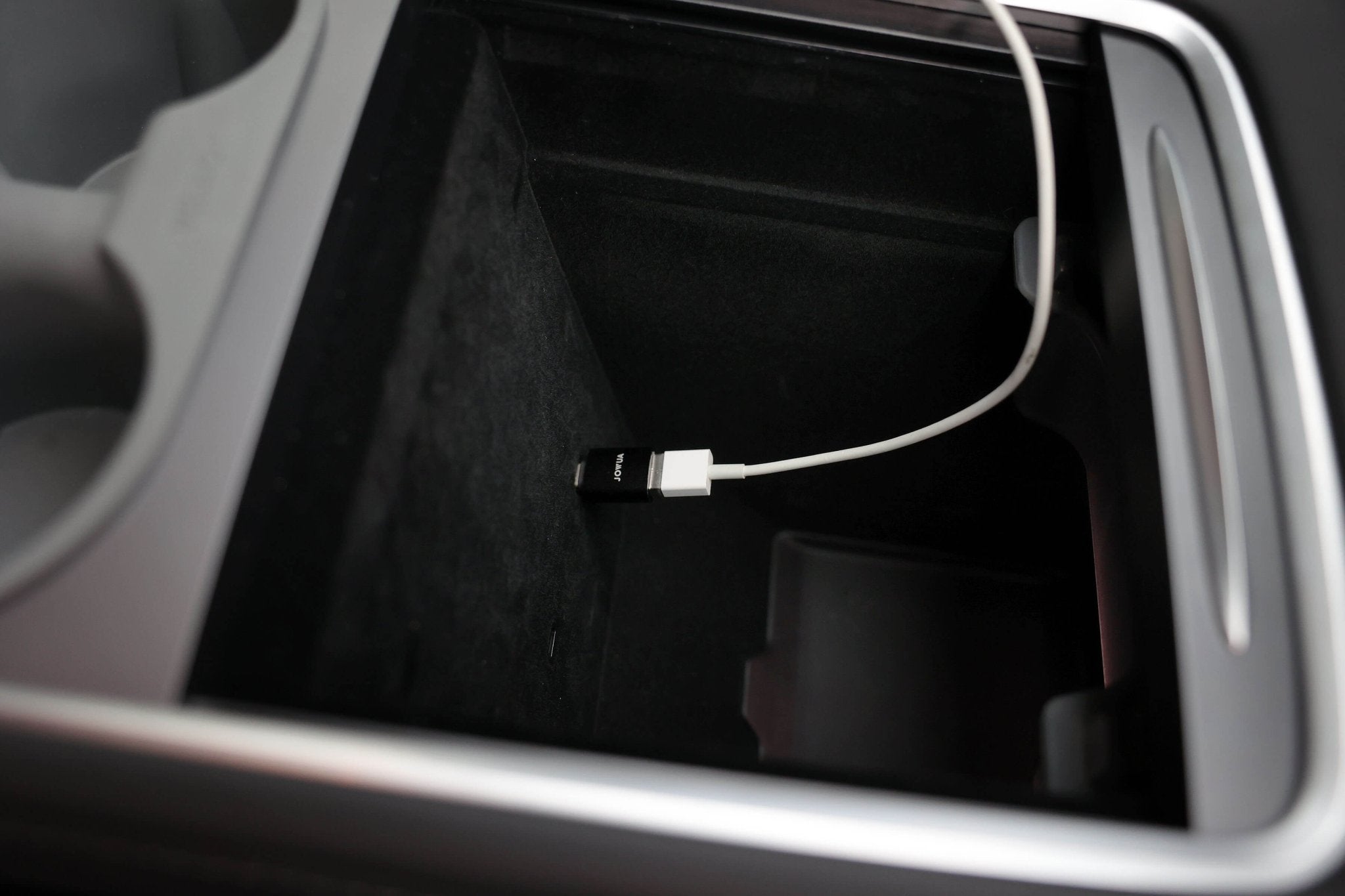 A close-up of a car's center console features the JOWUA Apple Watch Tesla Charging Kit with a USB-C to USB-A adapter, showcasing versatile charging options and Power Delivery support.