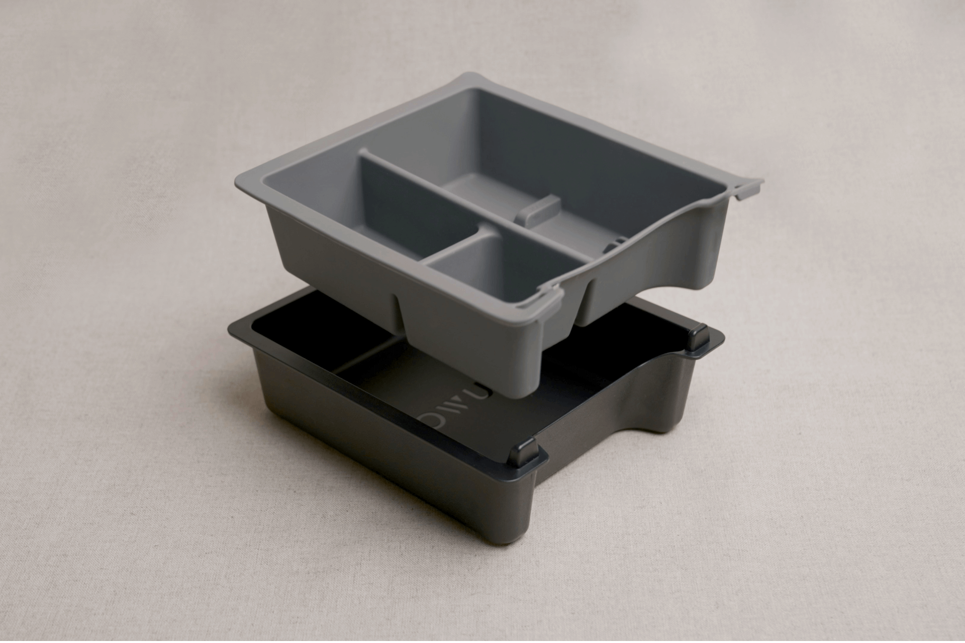 Displayed as a sophisticated center console solution, the Center Console Tray Organizer by JOWUA is perfect for Tesla Model 3/Y accessories. This set includes two nested trays: a top tray in gray with three sections over a darker bottom tray. Both trays are elegantly placed on a light beige surface and crafted from premium hybrid material to ensure lasting durability and style.