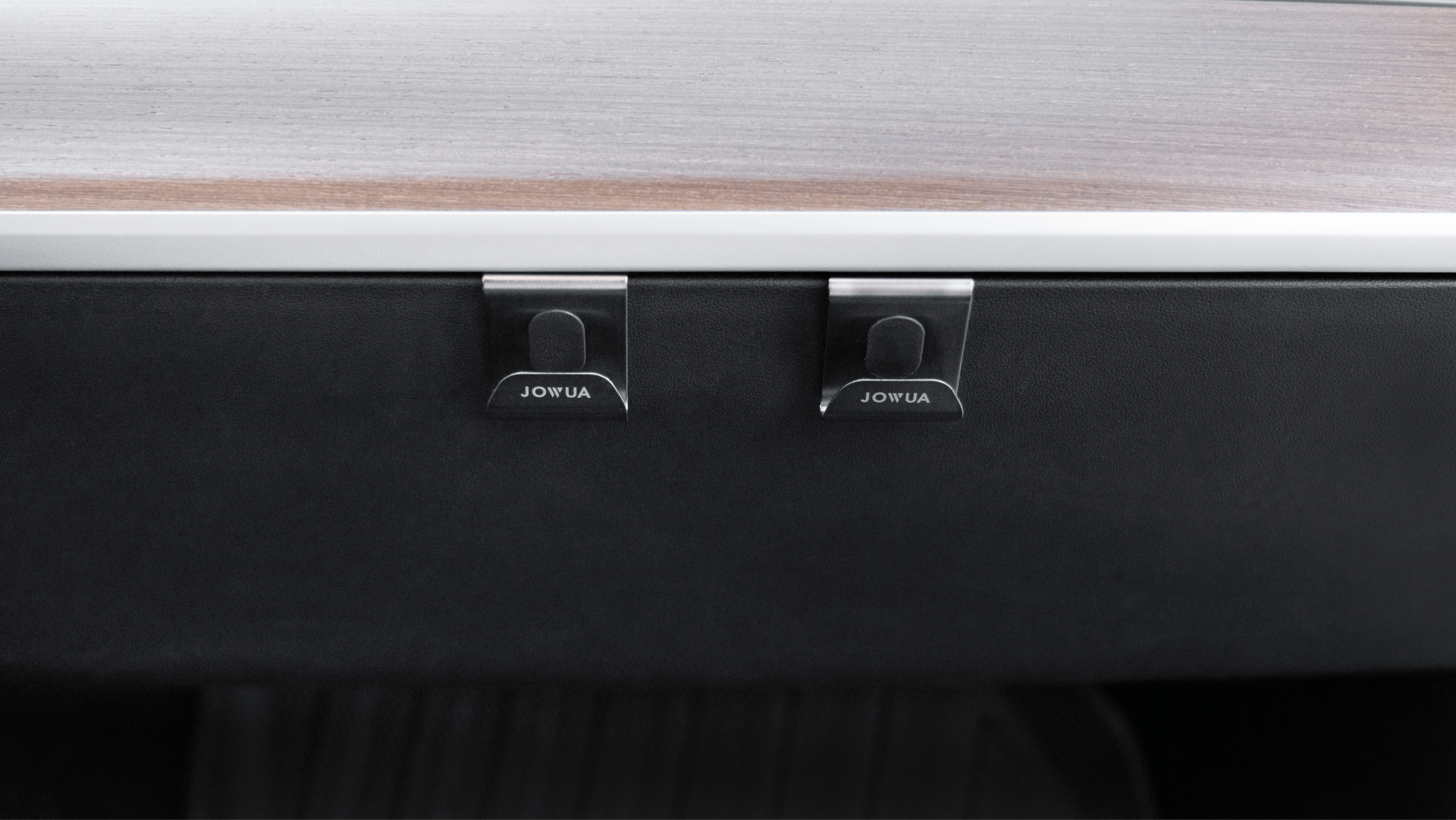 Close-up of two stainless steel hooks labeled "JOWUA" attached to a sleek black and wood-textured dashboard, perfect for the refined interior of a Tesla Model 3 or Y.