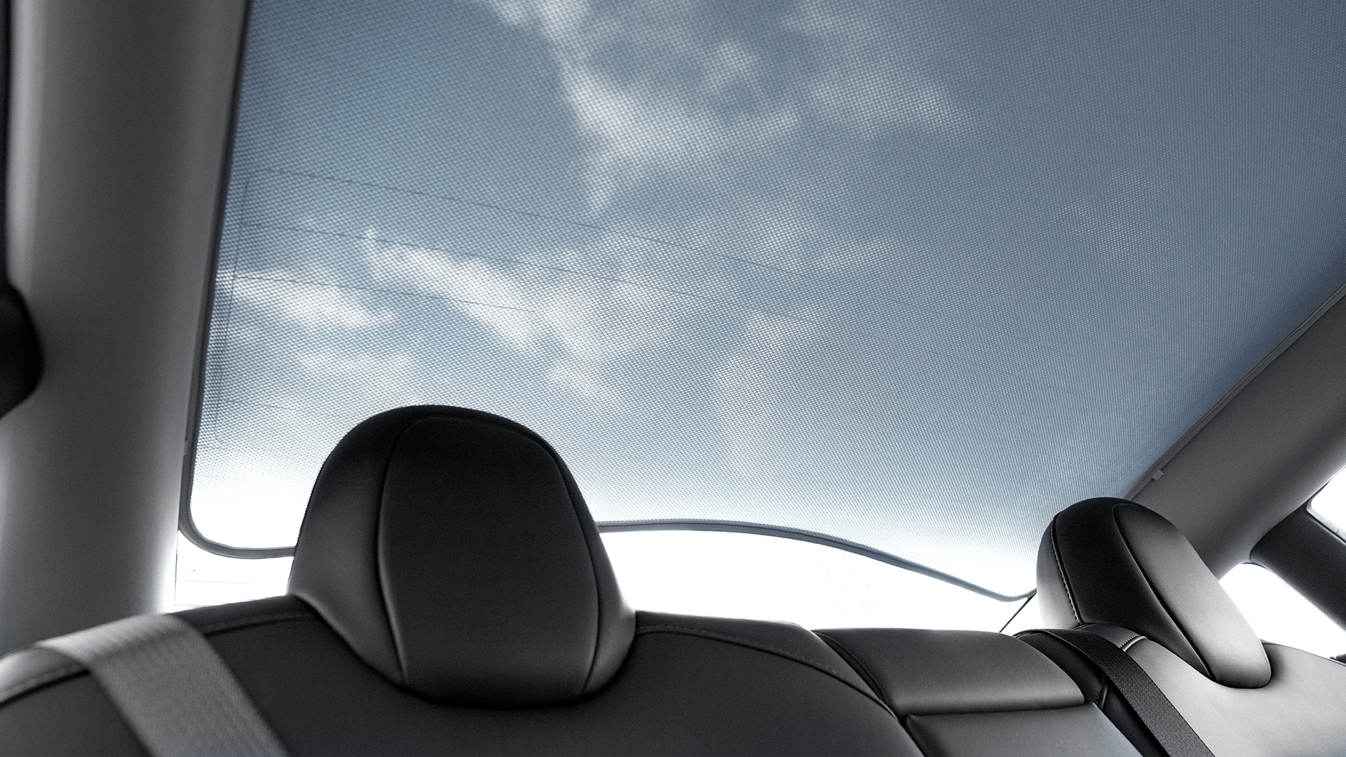 Enjoy a view through the Model Y (Juniper 2025+) panoramic glass roof, featuring UV protection, with black leather headrests and a seatbelt visible—pair it with the JOWUA Glass Roof Sunshade for added comfort.