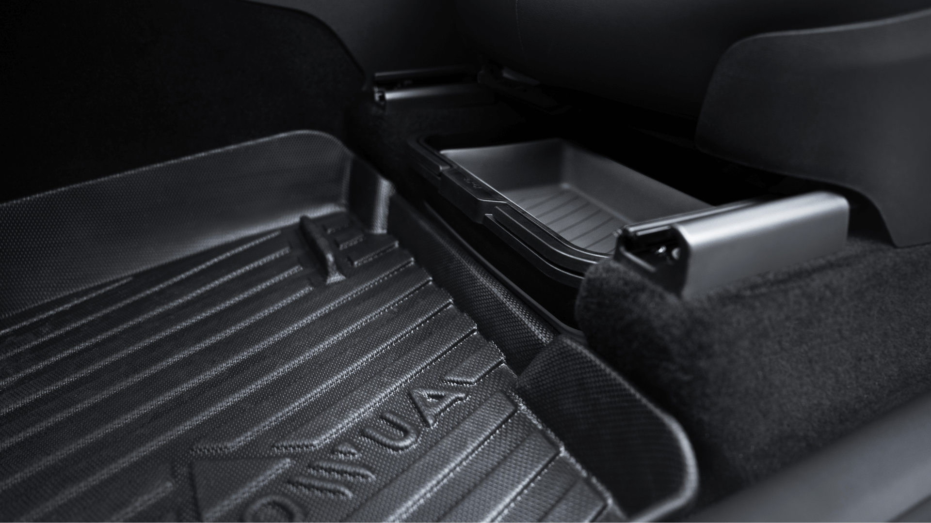 A close-up of a Tesla Model Y's rear passenger area features a textured floor mat labeled "INDIVIDUAL" and the JOWUA Under Seat Collapsible Organizer, designed specifically for Model X and Y vehicles. The dark interior is enhanced by contrasting highlights on these versatile components.