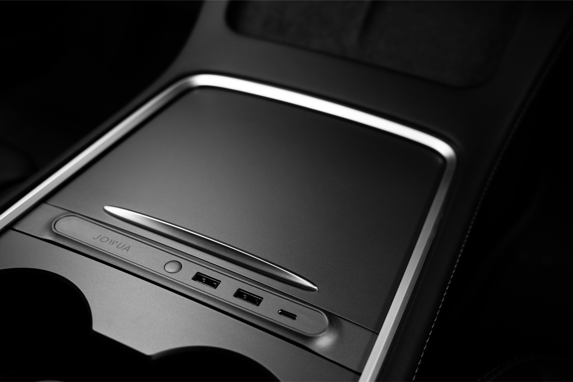 Close-up of a car's black and white center console showing a sleek, closed compartment with the 36W Hub Charging Combo by JOWUA, featuring two USB ports. The minimalistic design emphasizes smooth lines and a modern aesthetic.