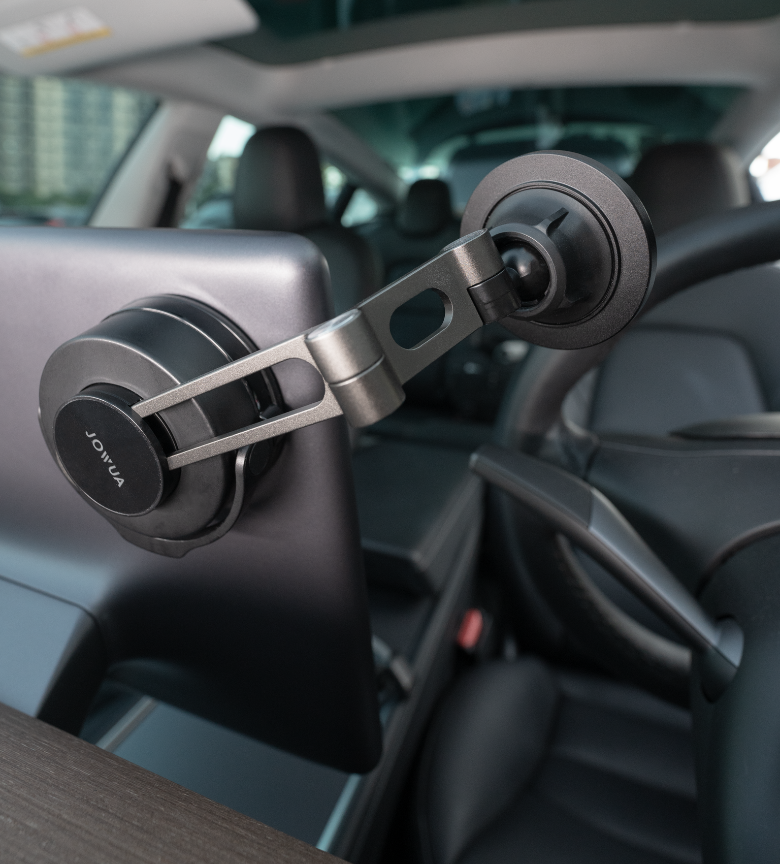A close-up of a smartphone holder with a suction cup mount attached to the interior of a car, focusing on its modern design and adjustable arm.