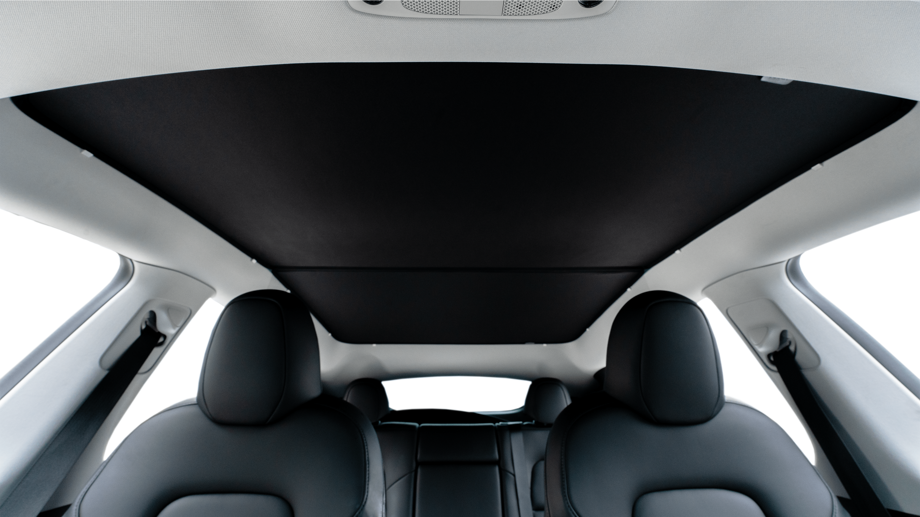 Interior view of a car showing sleek, modern black leather seats and a panoramic glass roof with a sunshade. The overhead console is visible against the light interior ceiling.