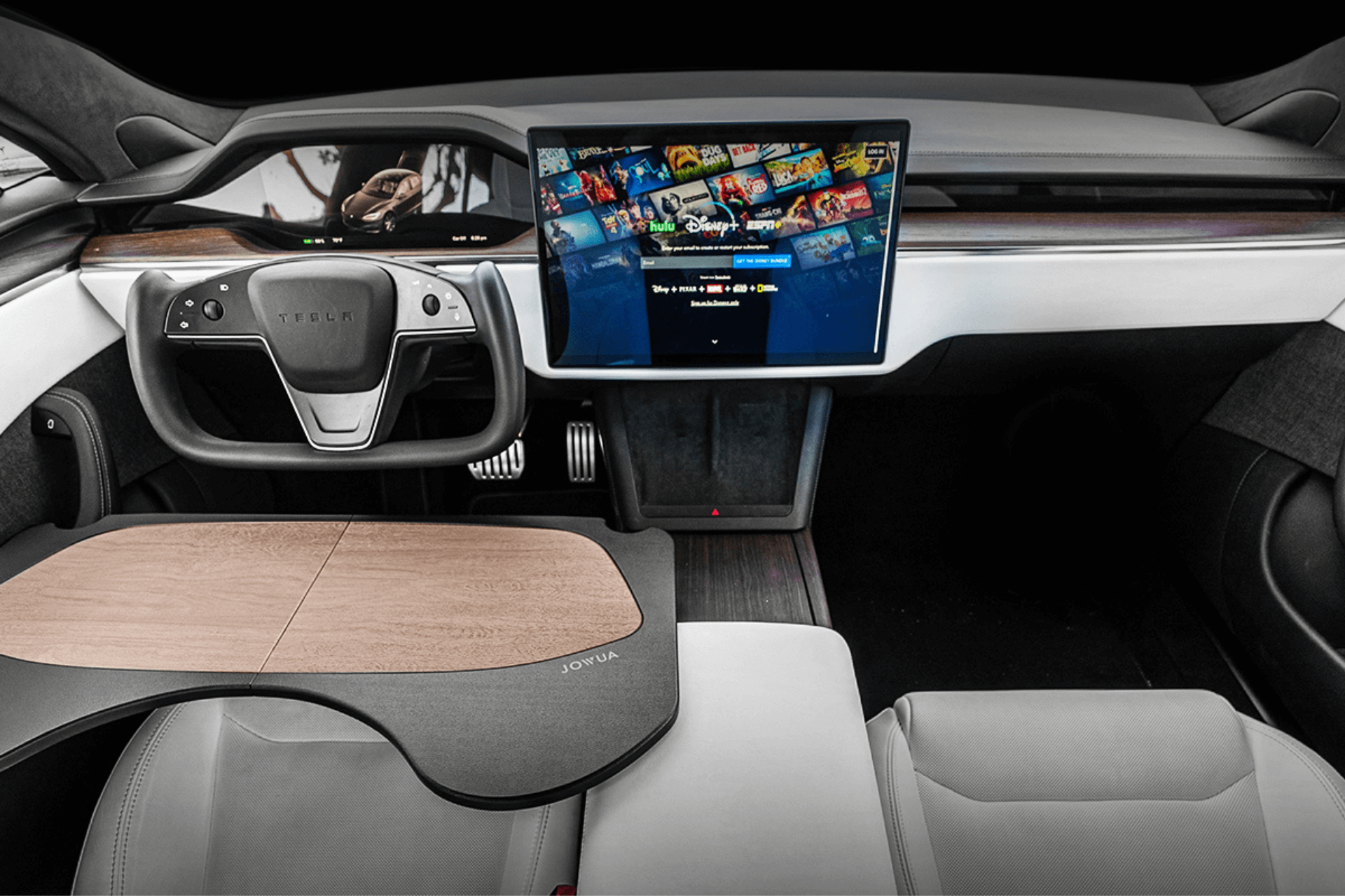 The image shows a futuristic car interior with a central touch screen displaying a streaming service. The steering wheel is sleek and modern, and the seats are leather. A wooden folding table is attached to the seat.