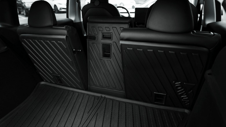 Back view of a car's interior focusing on the folded rear seats, displaying a modern and sleek design with textured surfaces. The seats are folded to maximize cargo space.