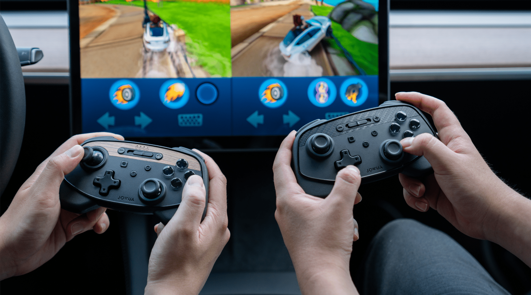 Two individuals holding wireless game controllers are playing a racing video game on a split-screen display. The screen shows colorful, animated race tracks with icons and controls visible on the screen.