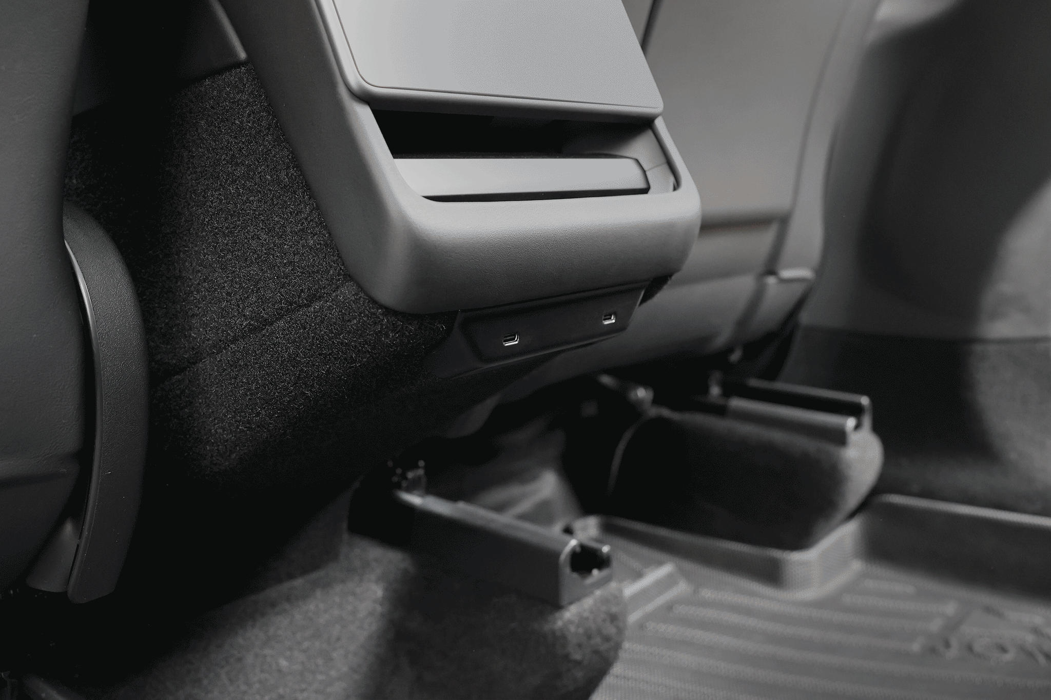Close-up view of a car’s back seat featuring visible floor mats and the JOWUA 130W LED Rear Vent Hub for Model 3 Highland (2024+)/Model Y Juniper (2025+), installed on the rear of the center console.