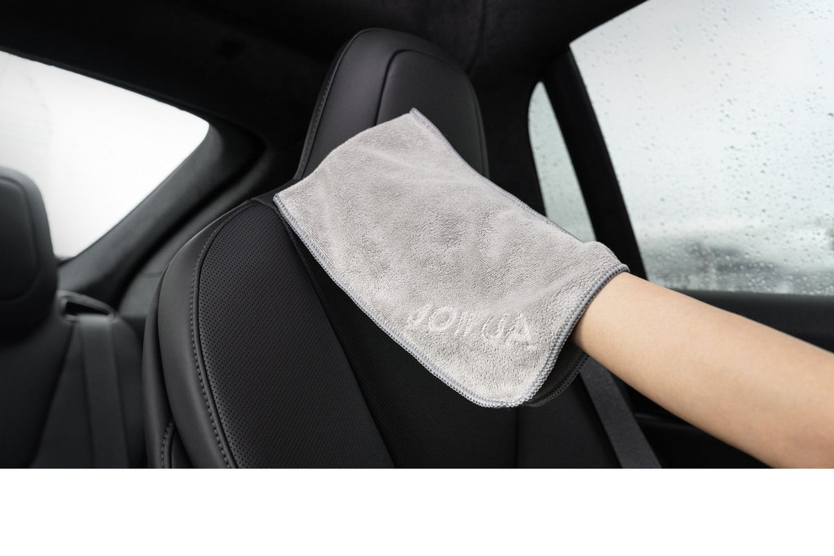 A person wipes a car seat headrest with the JOWUA Microfiber Cleaning Cloth as raindrops dot the window, while the JOWUA Under Seat Collapsible Organizer keeps the interior neat. Available as a combo set.