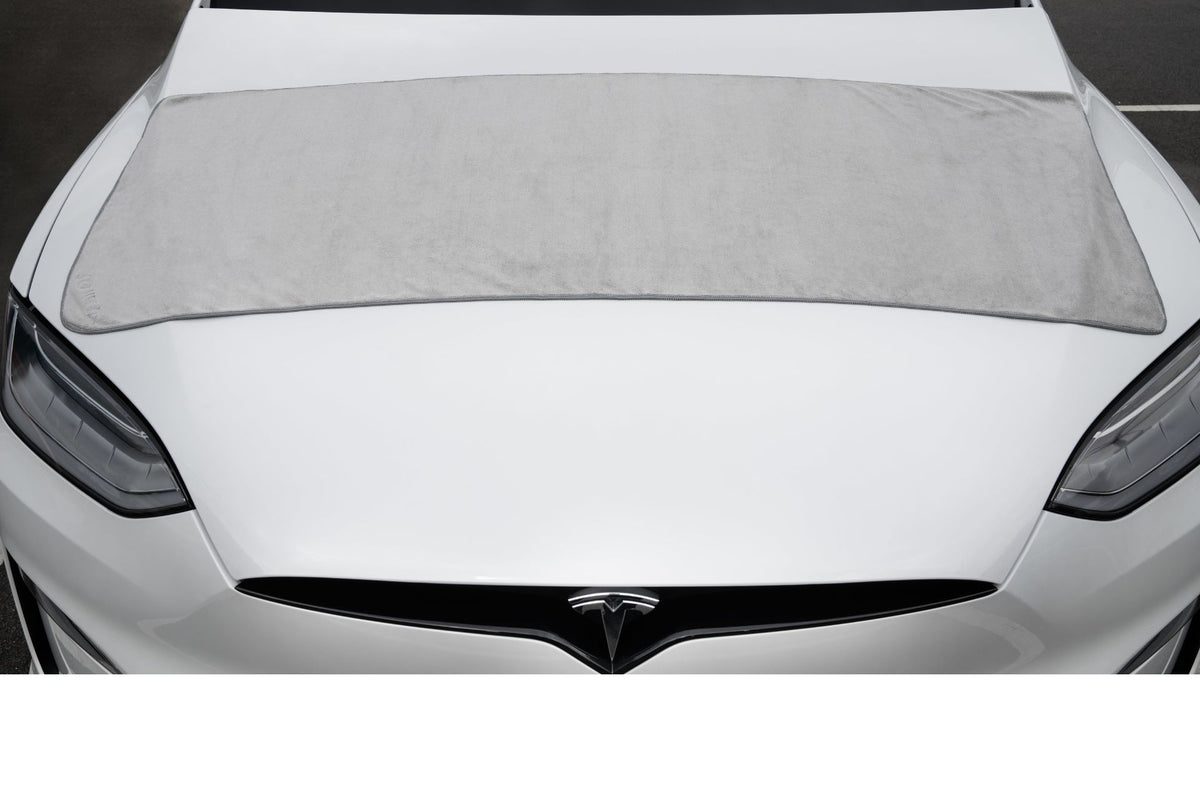 A JOWUA Under Seat Collapsible Organizer & Microfiber Cleaning Cloth Combo is shown with a white Tesla, the microfiber cloth resting nearby for convenient cleaning.