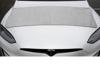A white car in a parking lot is covered by a gray microfiber cloth from the JOWUA 3 Pack, with its distinct headlights and emblem subtly visible, enhancing its elegance.