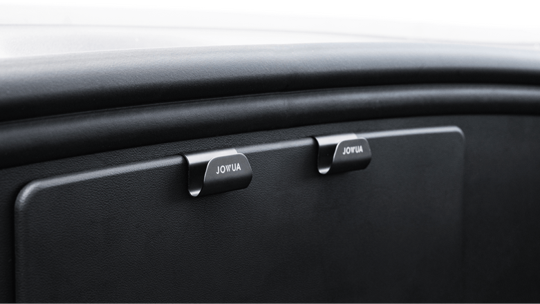 Close-up of a black car dashboard featuring two glovebox handles labeled "JOWUA Taiwan," with a discreet hook from the Hook Bundle (Model Y) for added convenience.