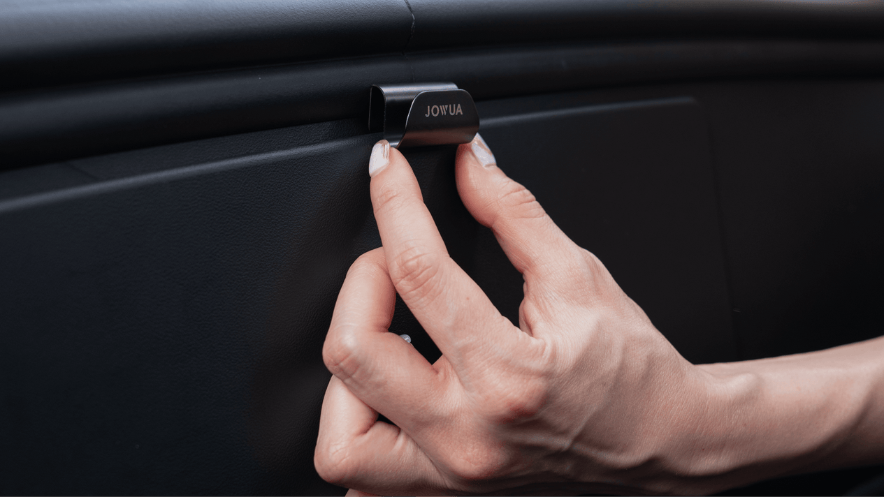 A person with manicured nails is adjusting a "JOWUA" Front Trunk Hook inside a Model S. The hand is positioned to open or secure the hook, showcasing the sleek interior detail.