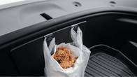 A plastic bag filled with fried chicken hangs from two JOWUA hooks inside the tidy trunk of a Model Y Juniper, highlighting the Premium Interior Essentials Set (RHD) by JOWUA.