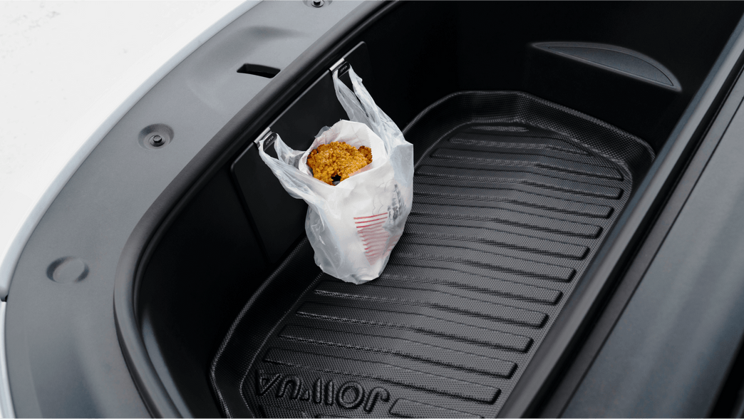 A plastic bag holding food items, including a container of popcorn, is neatly hung on the JOWUA Front Trunk Hook in the front trunk storage of a Model Y. The open trunk reveals its clean, lined interior.