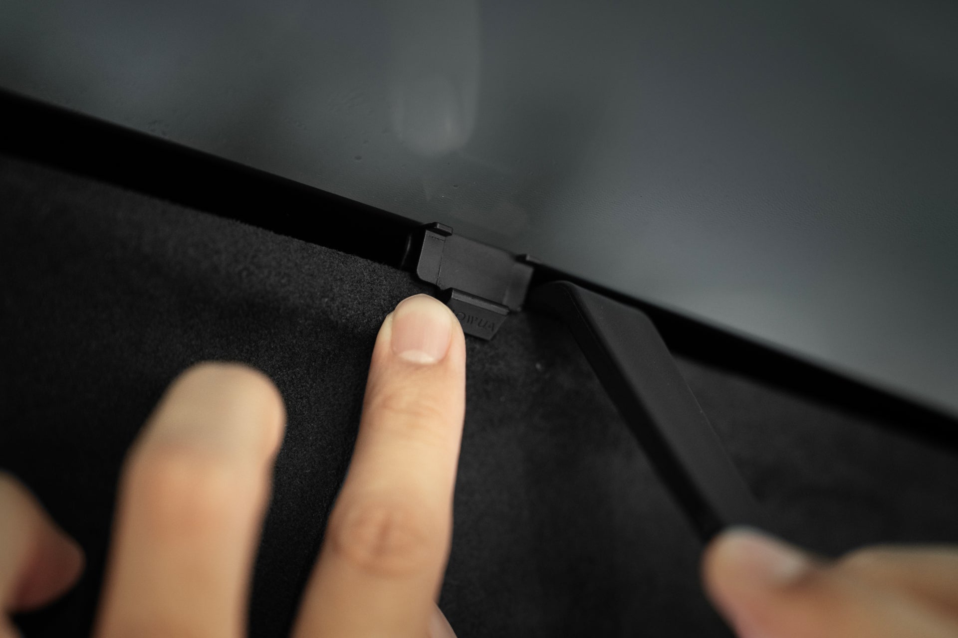 A close-up shows a hand pressing a black latch on the edge of a glass panel, likely part of the JOWUA Model X Separate Sunshade Bundle, suggesting an adjustment for better heat insulation.