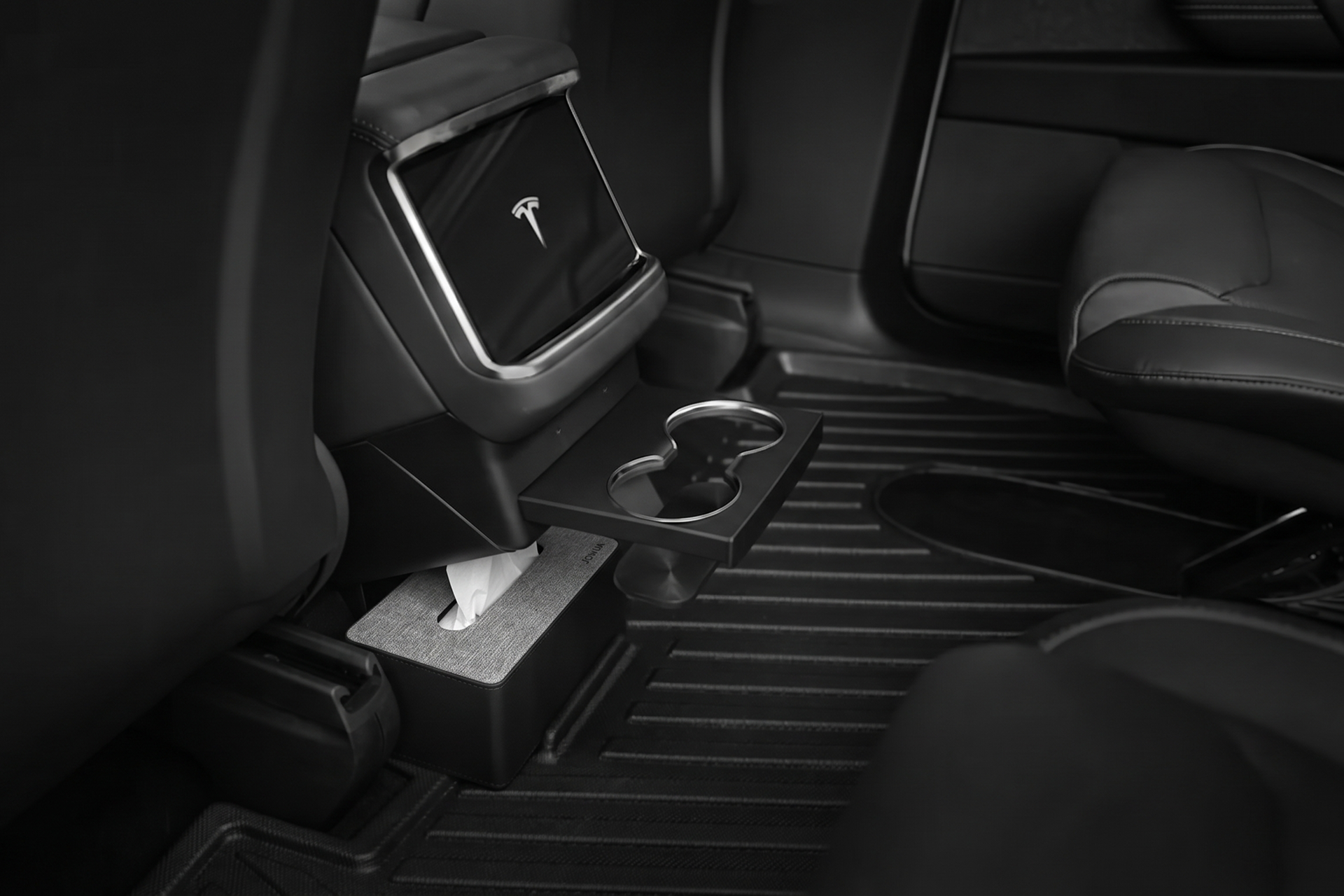Black and white photo of a Tesla’s back seat showcases JOWUA Model X All-Weather Floor Liners, center console with a tissue box, fold-out cup holder, and sleek seats for a clean, modern interior.