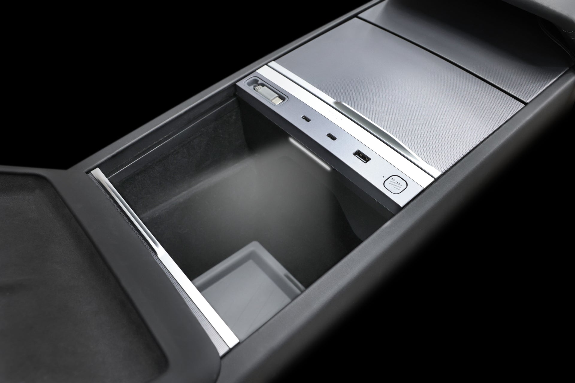 The interior view of a Tesla center console reveals the open storage compartment of the JOWUA 130W LED Hub, designed for Model Y Juniper 2025+ and Model 3 2024+. It features sleek, modern design elements with metallic accents against a dark interior backdrop.