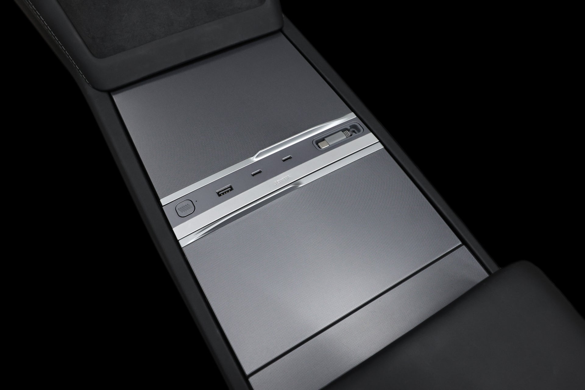 Close-up of the JOWUA 130W LED Hub for Tesla Model Y Juniper 2025+ / Model 3 2024+, showcasing a sleek, minimalist center console design with dual USB ports, a dynamic power management system featuring a 12V outlet, and an electronic device slot, all set against a metallic finish in dark surroundings.