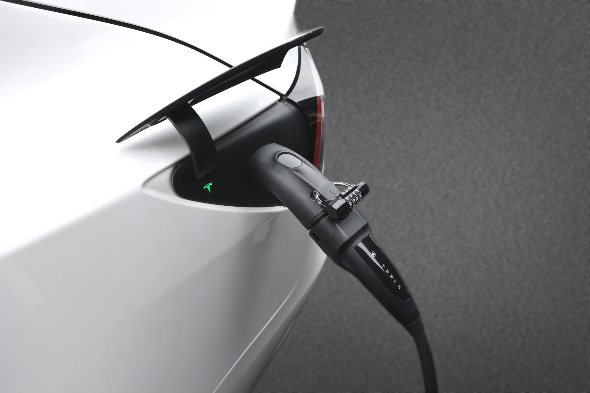 Close-up of a white EV charging with the JOWUA CCS2 to NACS DC/AC Charging Adapter Set plugged in, demonstrating broad compatibility against a grey background.