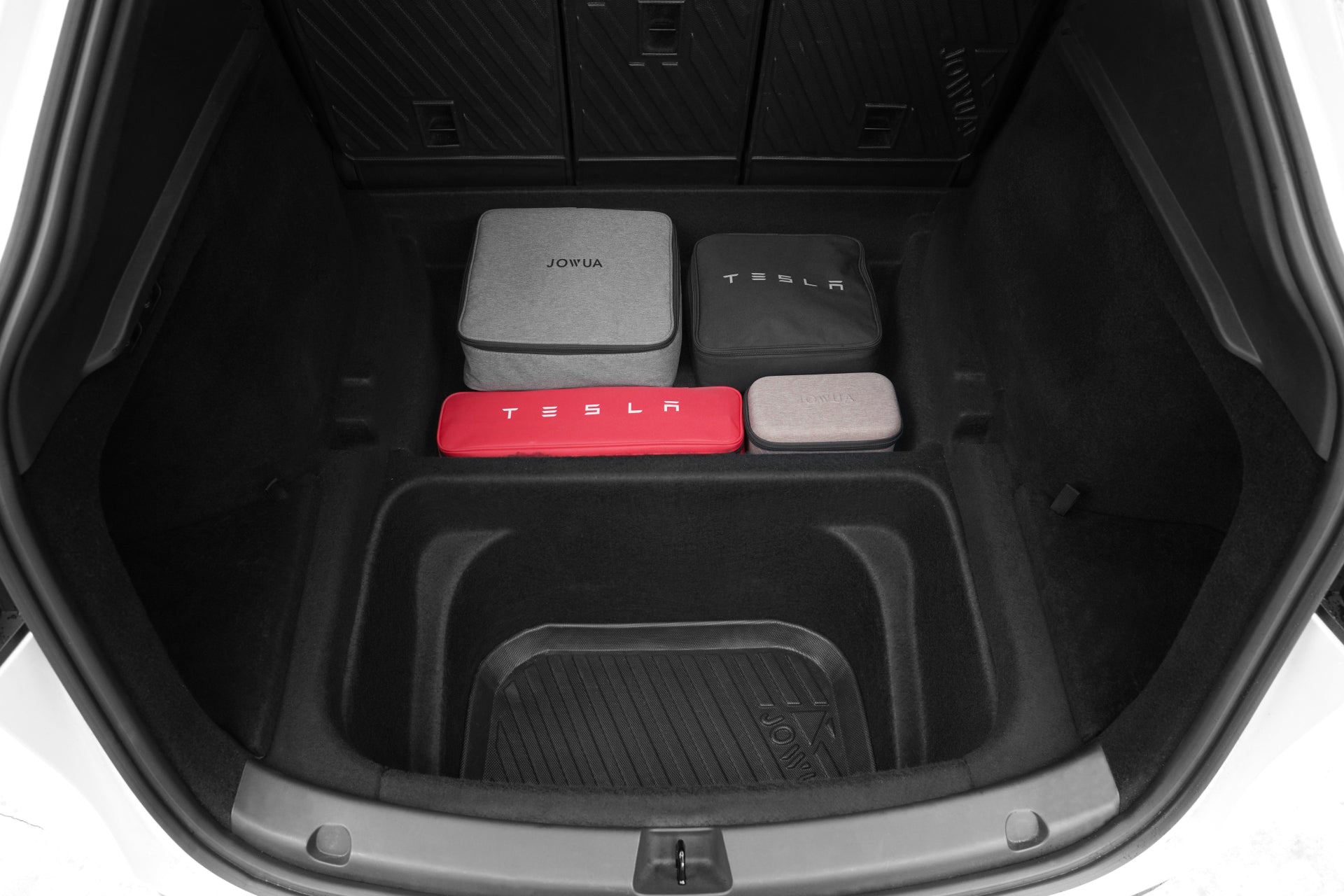 A Model Y trunk features the JOWUA EasyShield Waterproof Trunk Liner + Rear Seats Back Cover Bundle (Juniper 2025+/2018-2024) with four stylish storage cases in gray, red, and beige—perfect for keeping your Tesla neat and organized.