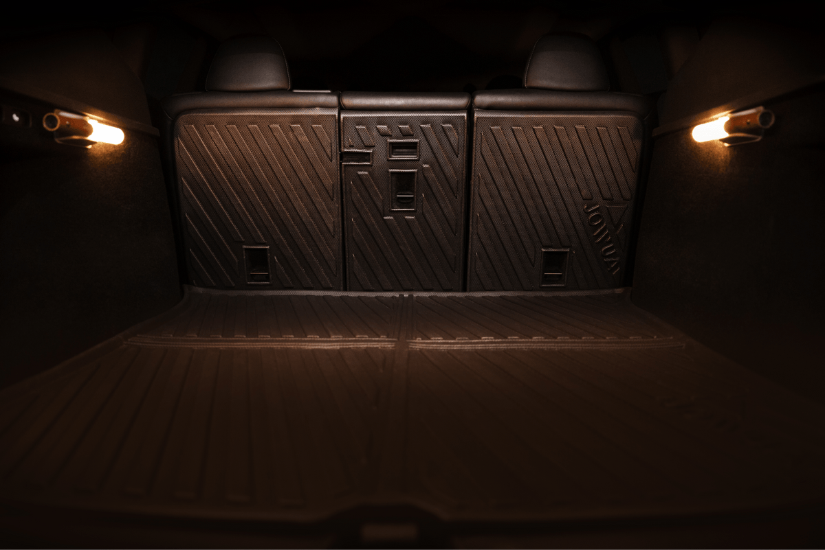 The image features the JOWUA Trunk Storage Bins Bundle for Model Y (2018-2024) with dark, textured rubber mats and a silicone storage box on the trunk floor, illuminated by two small side lights.
