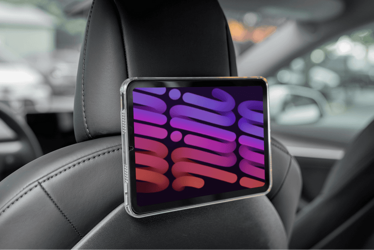 A JOWUA Hook Bundle Model 3 Highland 2024+ with an abstract pink and purple tablet is secured to a black leather car seat. The softly blurred background reveals the car's interior.
