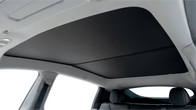Interior view of a car with a JOWUA All Model Y Glass Roof Sunshade (Juniper 2025+ / 2021-2024), featuring a black mesh fabric cover partially shading the panoramic window for UV protection. The frame is light-colored, and seats are visible in the image