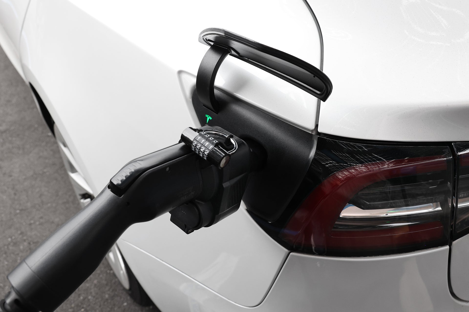 A close-up of a white electric car being charged with a JOWUA CCS1 to NACS DC & AC Charging Adapter plugged into the port on the rear side.