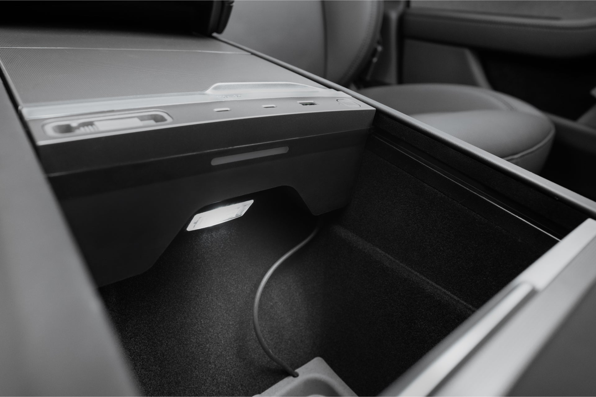 Interior view of a Tesla Model Y Juniper 2025+ with the JOWUA 130W LED Hub, featuring a storage compartment with LED lighting and dynamic power management. A USB port and control panel offer efficient charging and storage solutions extending to the armrest.