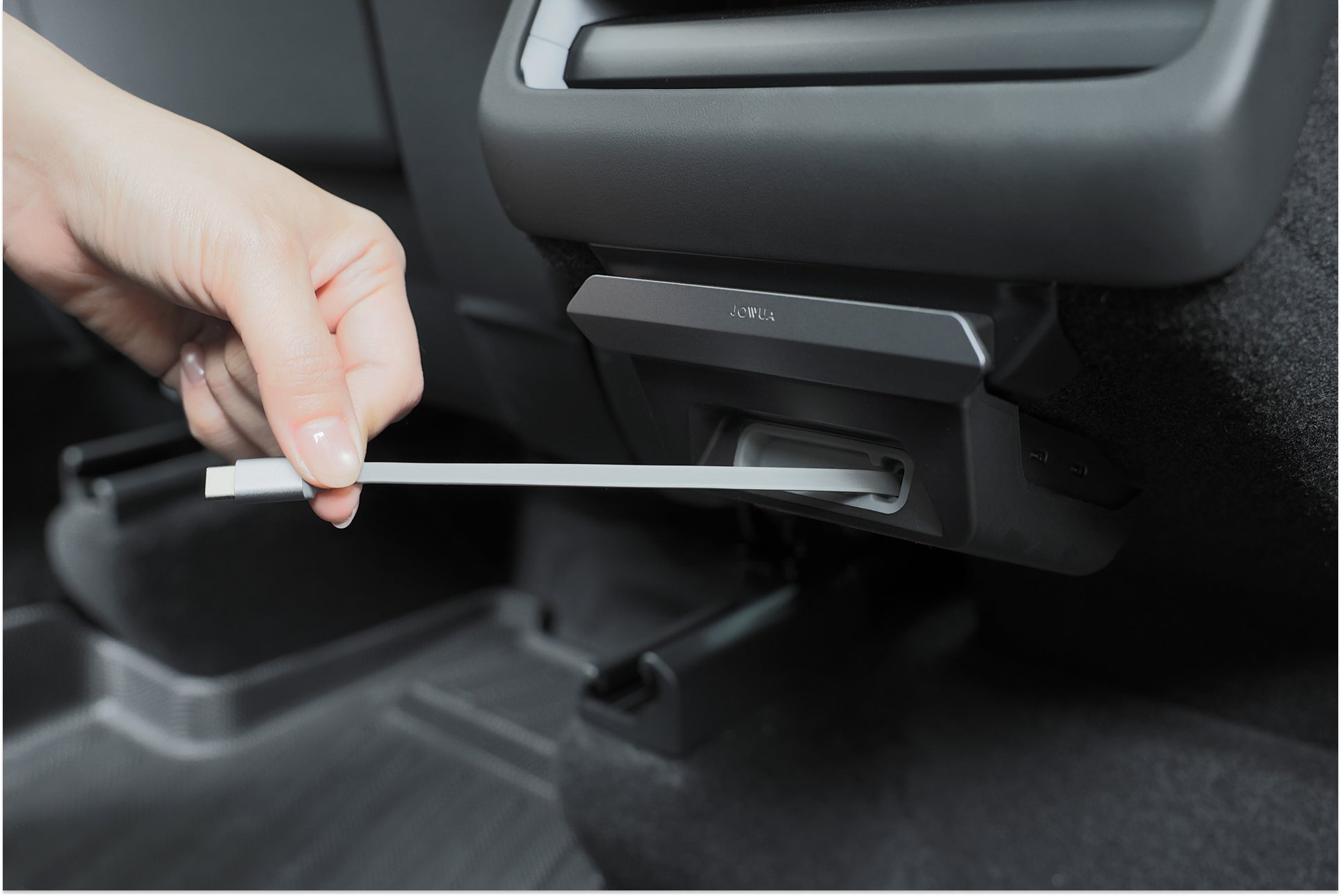 A hand plugs a white charging cable into the JOWUA 130W LED Rear Vent Hub (Model 3 Highland 2026+ / Model Y Juniper 2026+), mounted on the back seat inside a vehicle.