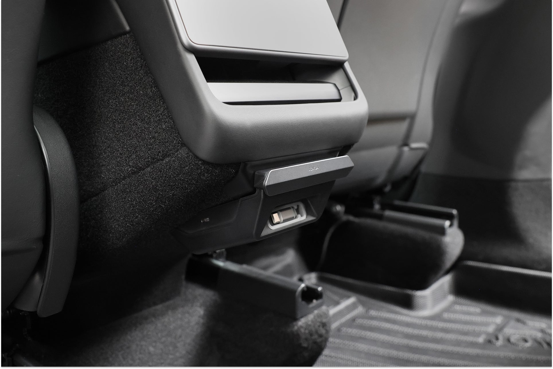 Close-up of the rear center console showcasing the JOWUA 130W LED Rear Vent Hub for Model 3 Highland 2024+ / Model Y Juniper 2025+, with fast USB-C charging, air vent, black carpeted floor, and part of the back seat visible.