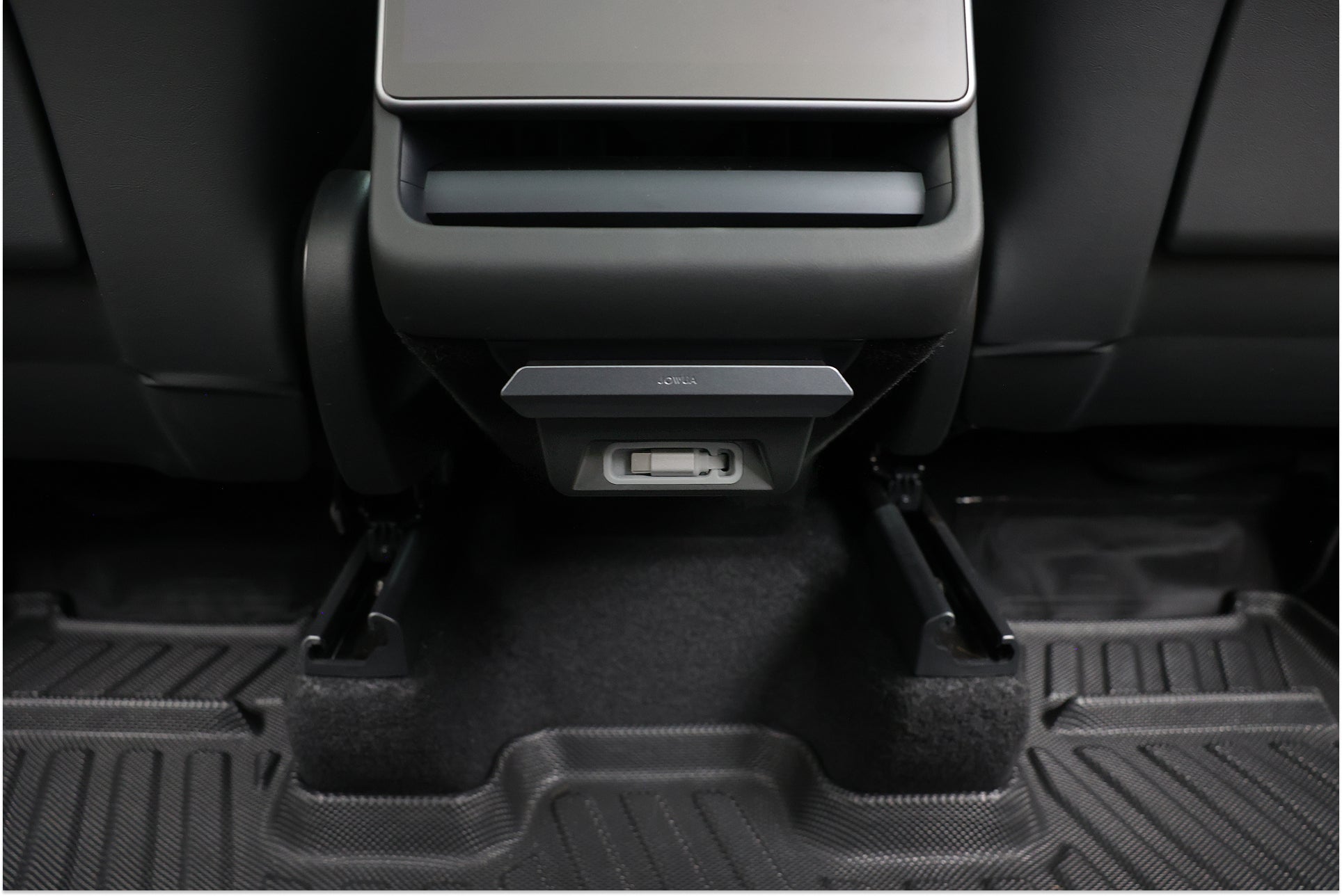 Backseat view showing two front seat backs, a center console with the JOWUA 130W LED Rear Vent Hub (Model 3 Highland 2024+/Model Y Juniper 2025+), and custom floor mats covering the carpeted floor.