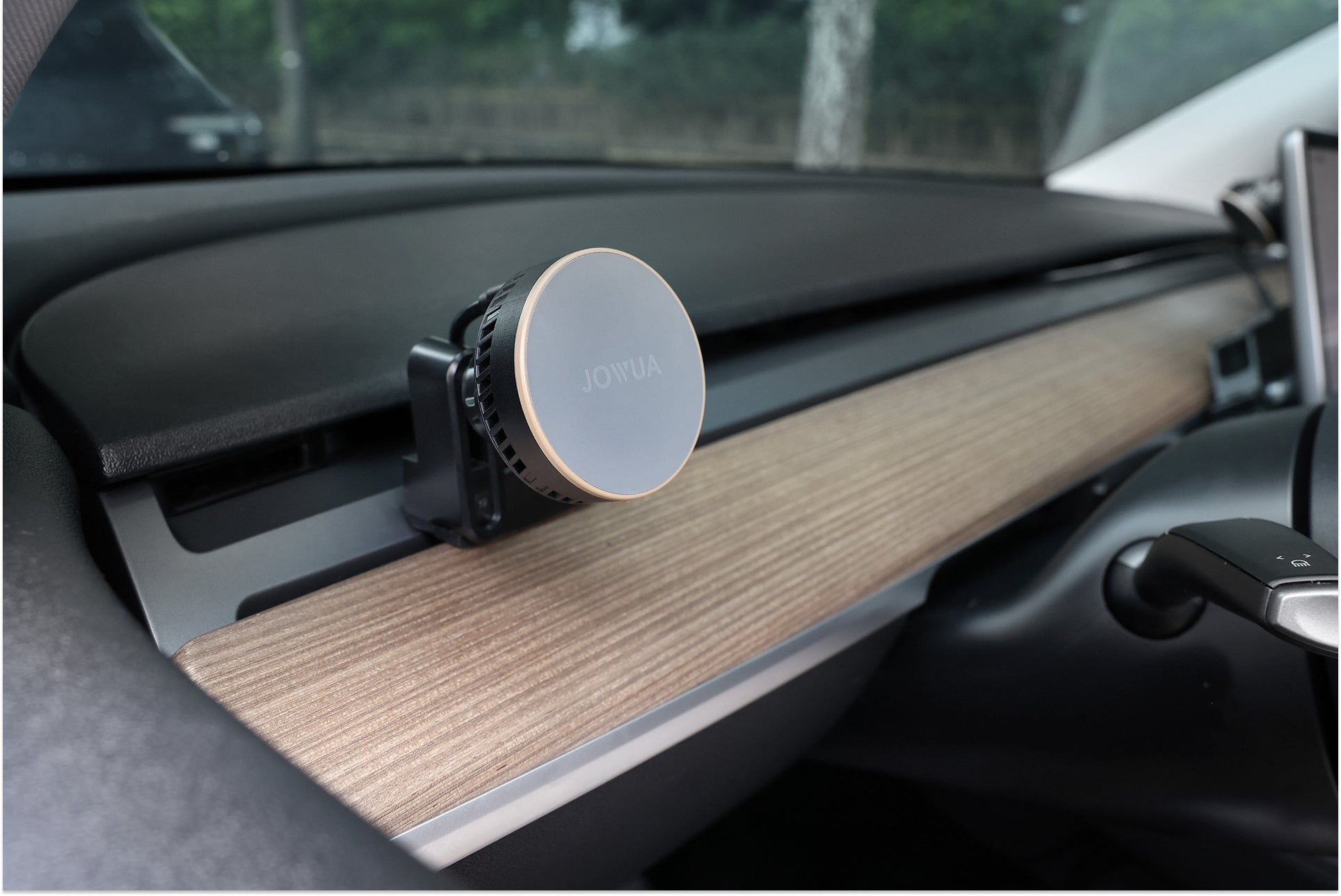 A JOWUA Active Cooling MagSafe Car Mount for Air Vents (Model 3/Y 2018-2024) attaches to the minimalist wood trim dashboard, offering a sleek design and MagSafe wireless charging for easy convenience.