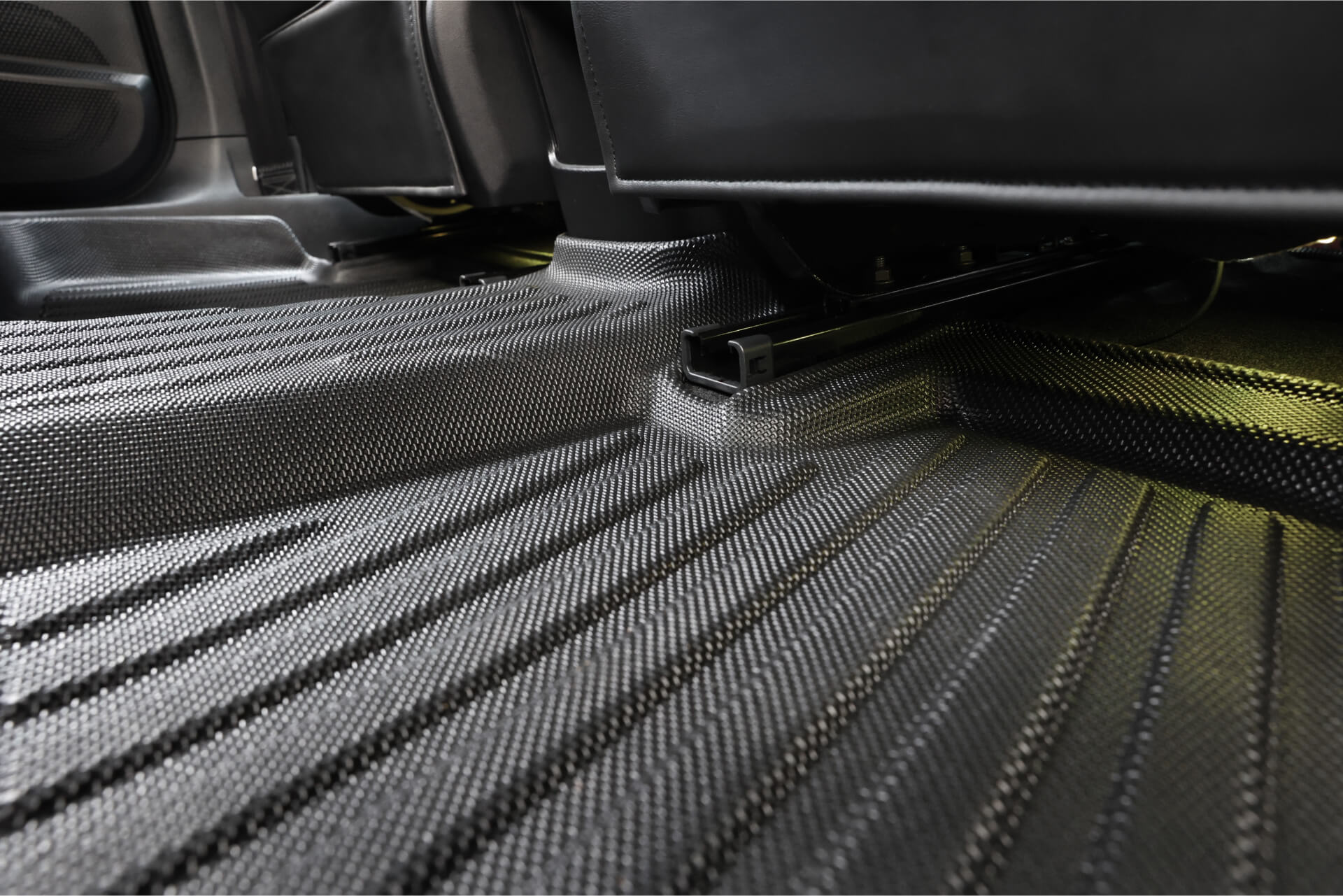 Close-up of the JOWUA All Weather Floor Liner (MG MG4) installed in the backseat, highlighting its textured black surface, contoured fit, and grooves designed to catch dirt and debris.