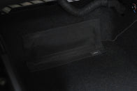 A close-up of a black mesh storage pocket attached to a carpeted interior, featuring the JOWUA label—part of the Premium Interior Essentials Set (RHD) for Model Y Juniper, perfect for those seeking premium car accessories.