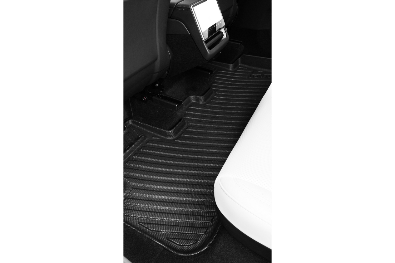A close-up of a Tesla Model Y (Juniper 2025+) rear interior shows JOWUA’s custom-fit black All-Weather Floor Liners Combo with raised edges, placed between the black front seat and white back seat.