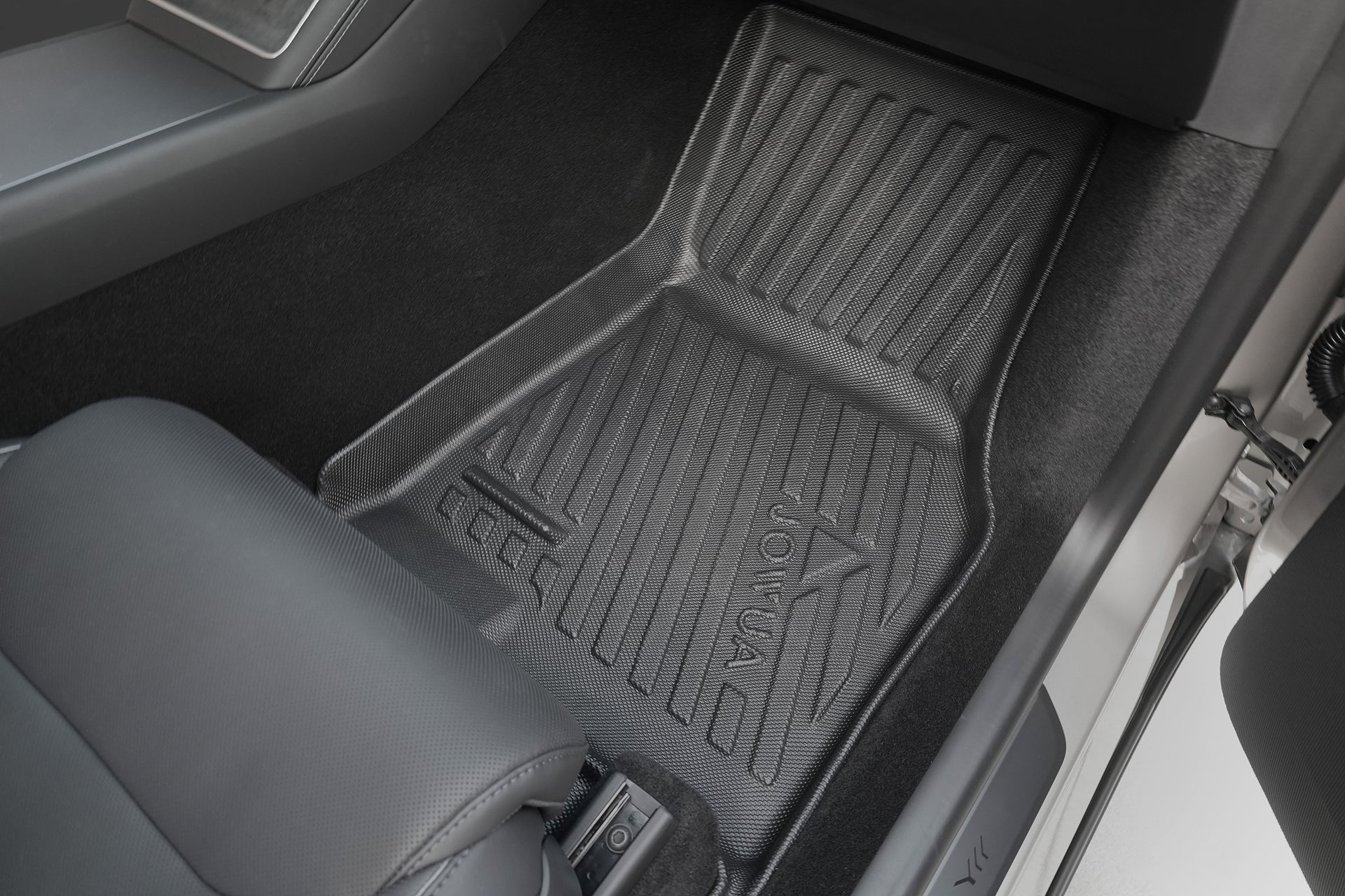 The JOWUA Model Y L (2026+) All Weather Floor Liner (Left Hand Drive Version) is shown in the front passenger footwell of a black interior Tesla, with a leather seat visible on the left side.