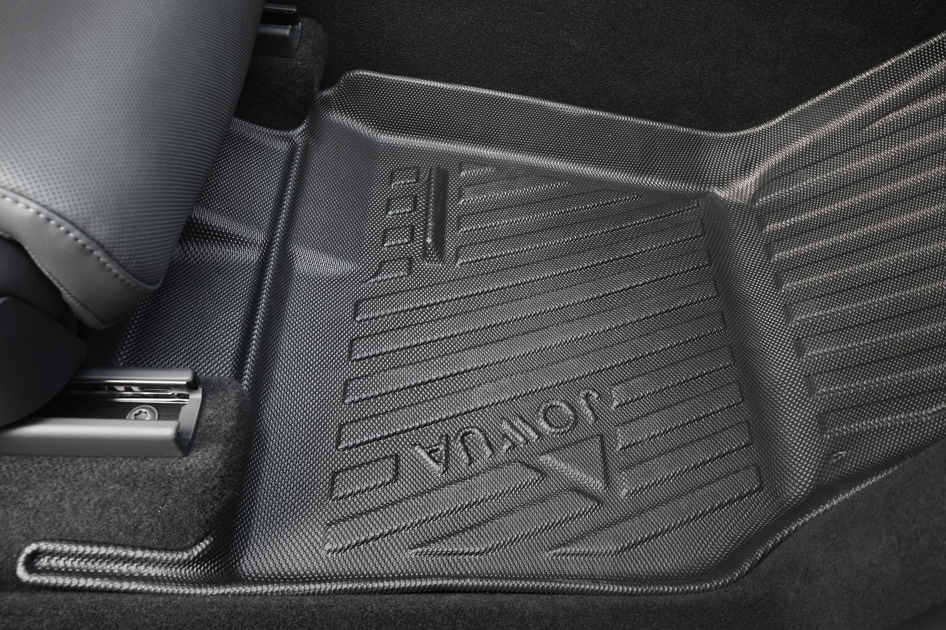 Close-up view of a textured black JOWUA Model Y L (2026+) All Weather Floor Liner (Left Hand Drive Version), placed on the vehicle’s carpeted floor beneath a gray seat.