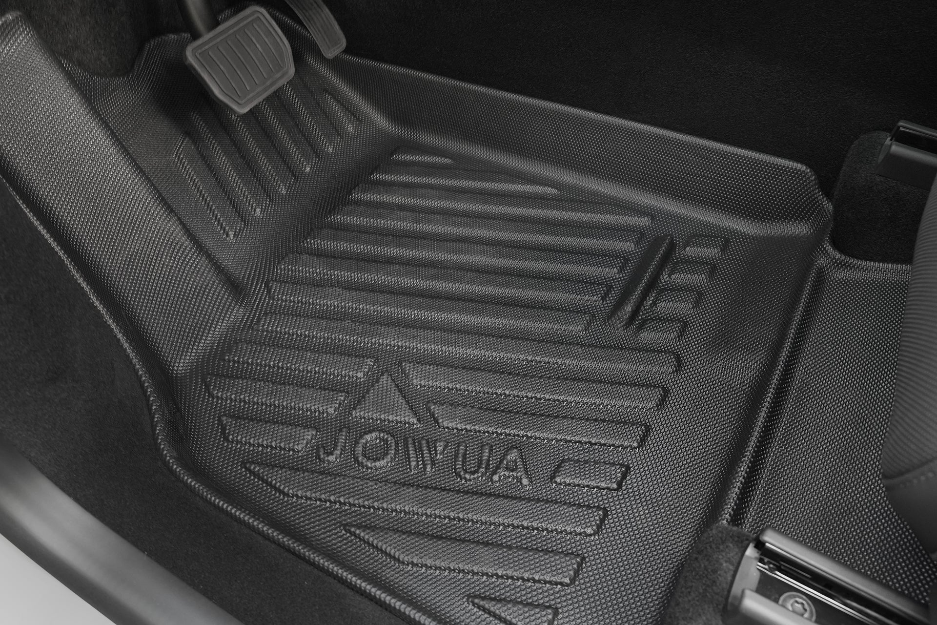 Close-up of a JOWUA Model Y L (2026+) All Weather Floor Liner (Left Hand Drive), textured black rubber with raised ridges, in the driver’s footwell near the pedals.