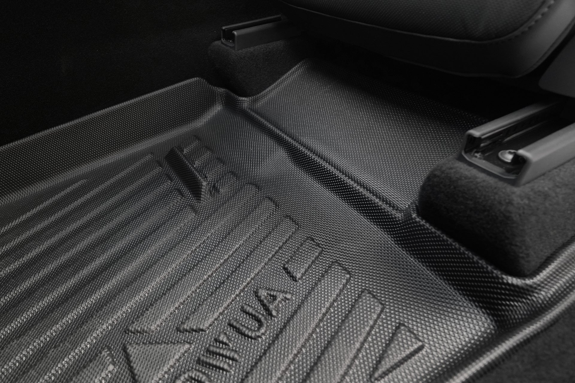 Close-up of the JOWUA Model Y L (2026+) All Weather Floor Liner (Left Hand Drive), featuring textured black grooves and raised edges for durable protection against dirt and debris between seat rails.