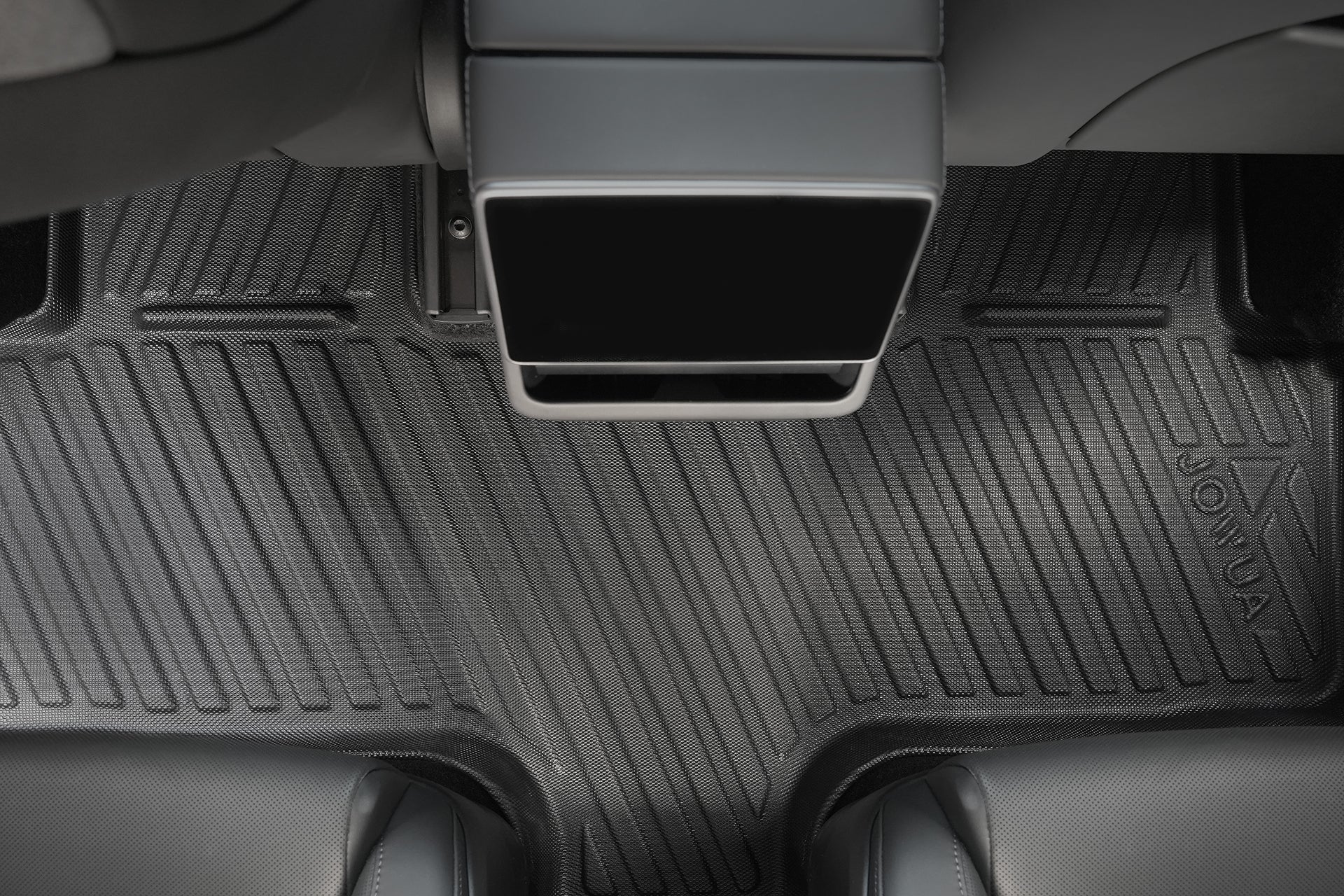 Close-up of a Model Y L (2026+) All Weather Floor Liner by JOWUA, showing its textured, grooved surface and embossed brand name, compatible with Tesla Model Y (LHD); lower portions of two car seats are partly visible.
