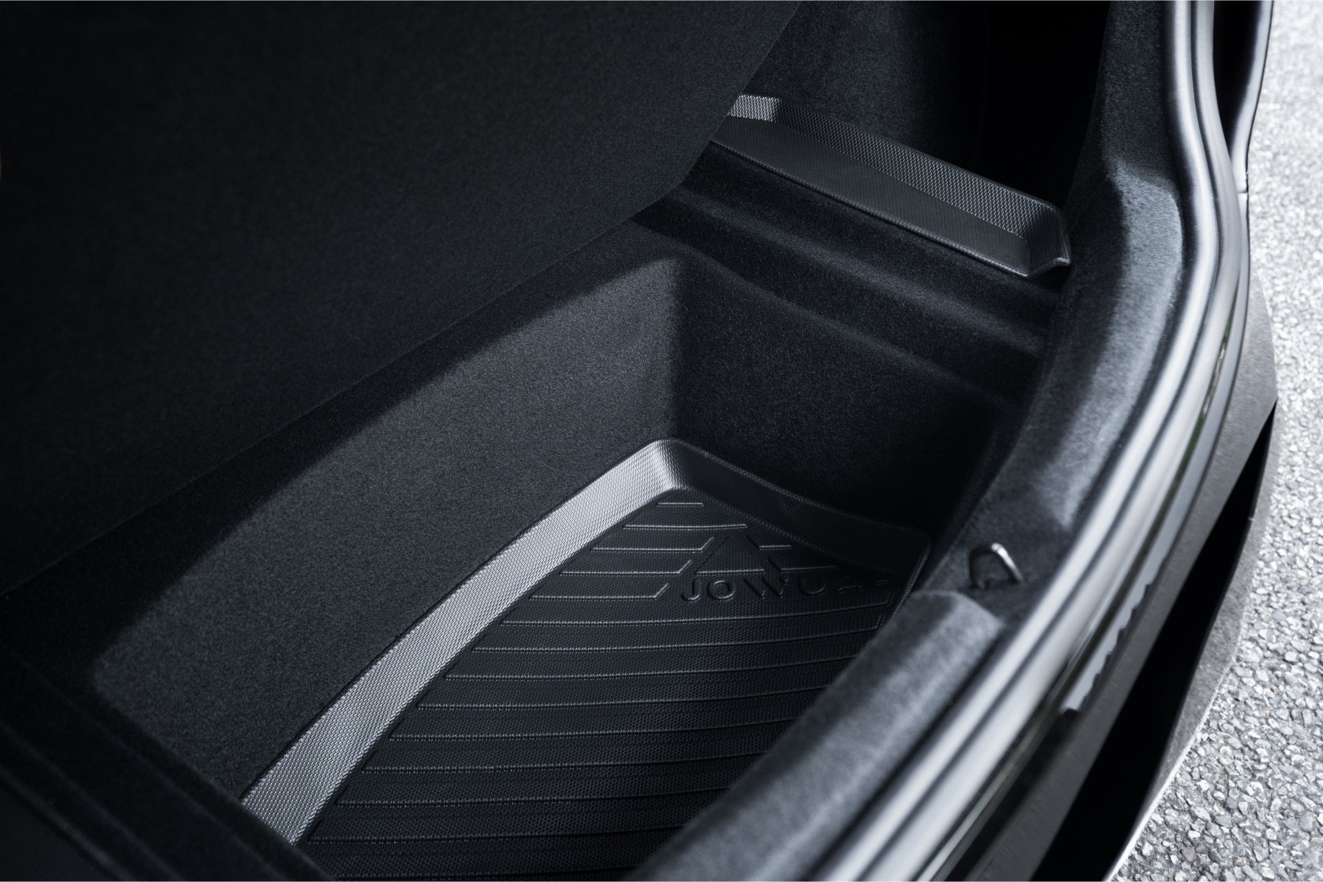 A close-up view of the JOWUA Model 3 All Weather Trunk Combo for the reengineered Model 3 Highland (2024+) displays a sleek, textured surface. Made from waterproof TPE material, this trunk features a dark-toned, logo-embedded design with a visible edge at the top.