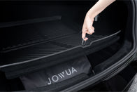 In the trunk of a Reengineered Model 3 Highland (2024+), someone lifts an all-weather floor mat featuring waterproof TPE material by a small handle. Underneath, a storage space is unveiled, revealing a bag marked with "JOWUA.