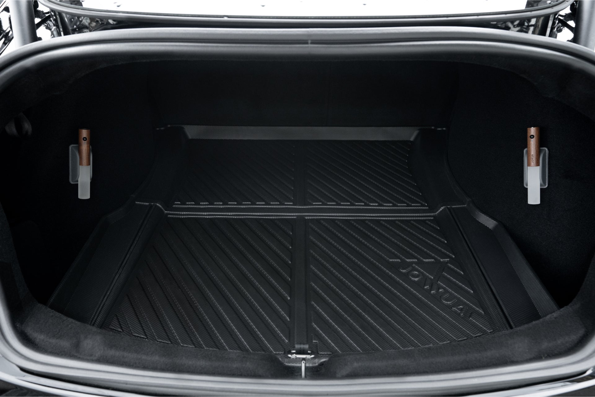 The open trunk of a Tesla Model 3, equipped with the JOWUA Model 3 All Weather Trunk Combo for the reengineered Model 3 Highland (2024+), reveals a black, ribbed rubber mat lining. This trunk liner is made from waterproof TPE material, displays a logo, and fits snugly within the space. It also features two clips on each side to ensure secure storage of items.