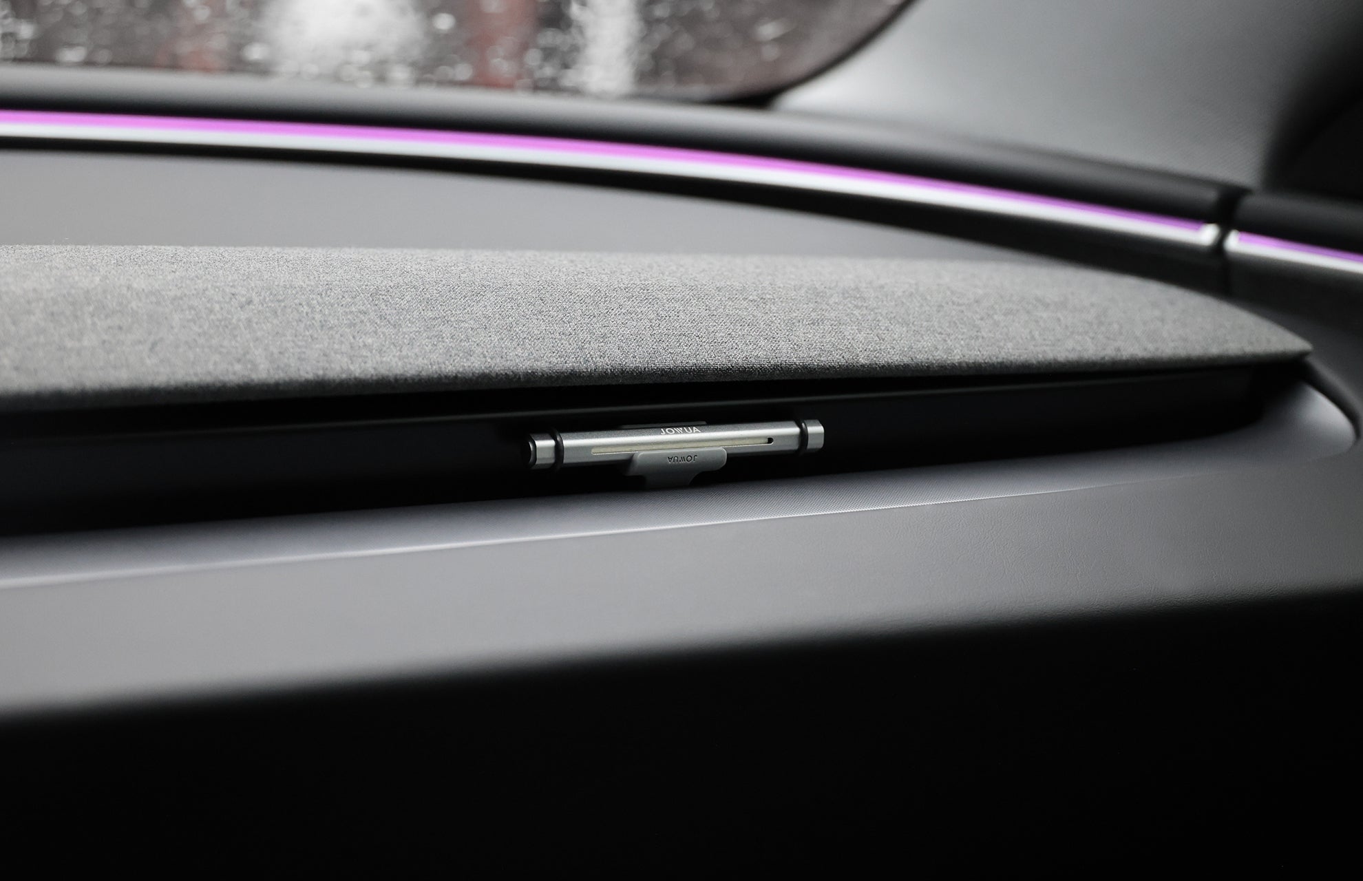 A sleek car interior features a fabric-lined compartment with a Montblanc pen in a recessed holder, lit by a purple LED strip and enhanced by the fresh aroma from the JOWUA Tesla Air Freshener for Model S/3/X/Y.