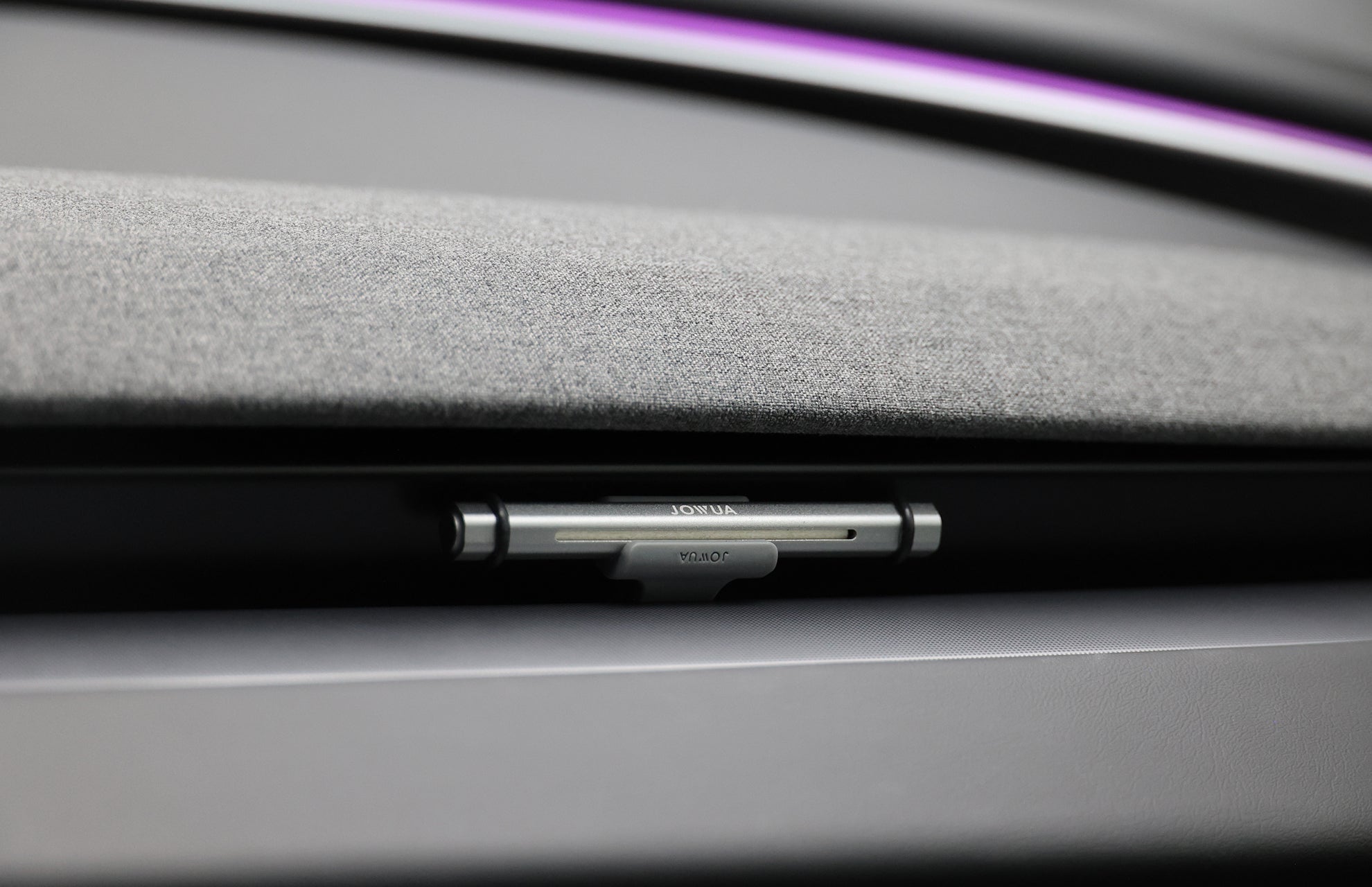 A close-up of a modern car's door lock shows a silver switch labeled "LOCK" and "UNLOCK," set in grey fabric and plastic, with a JOWUA Tesla Air Freshener for Model S/3/X/Y adding natural scents to the cabin.