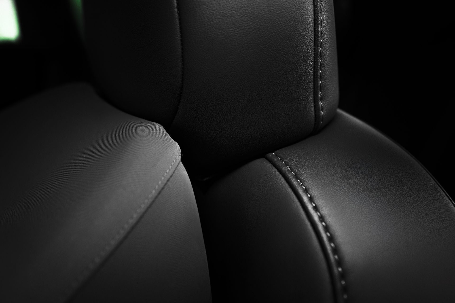 Close-up of JOWUA Car Neck Pillow on black leather seats, showcasing visible stitching, smooth textured surfaces, and ergonomic neck support that highlights the craftsmanship and quality upholstery.
